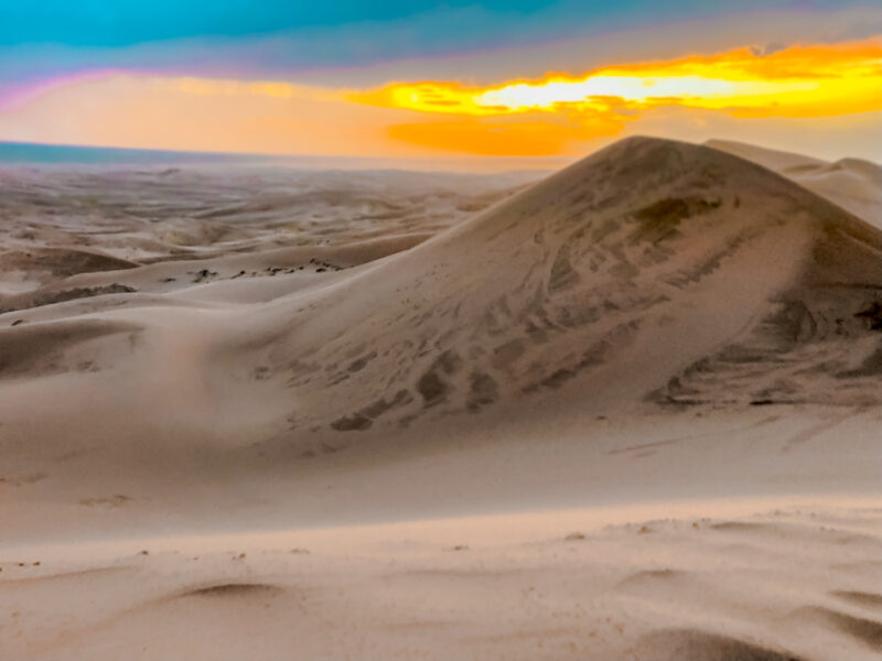 Sunset at the Khongor Sand Dunes. The Gobi in Mongolia is famous for the sand dunes. Therefore climbing the Khongor Sand Dunes is a must-do for any visitor to the Gobi! Learn about what to expect in summiting the great sand dunes. #sanddunes #mongolia #khongorsanddunes
