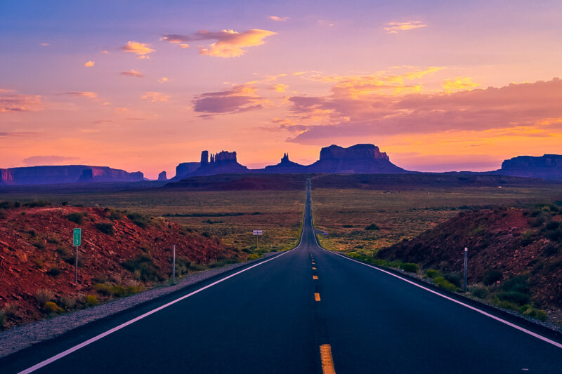 Road through the desert at Monument Valley. Monument Valley has two famous spots: sunrise of Mitten Buttes and Merrick Buttes, and then sunset at the famous Forrest Gump movie scene location. Learn about what to expect visiting Monument Valley, and how to capture the best photos while visiting! #monumentvalley #buttes #desert