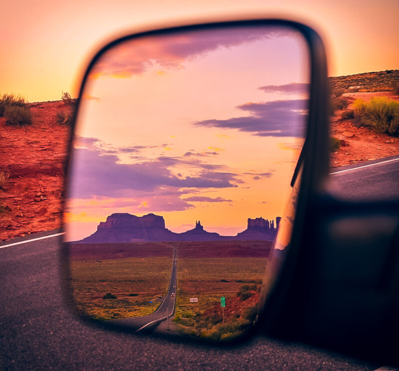 Desert in the side view mirror at Monument Valley. Monument Valley has two famous spots: sunrise of Mitten Buttes and Merrick Buttes, and then sunset at the famous Forrest Gump movie scene location. Learn about what to expect visiting Monument Valley, and how to capture the best photos while visiting! #monumentvalley #buttes #desert