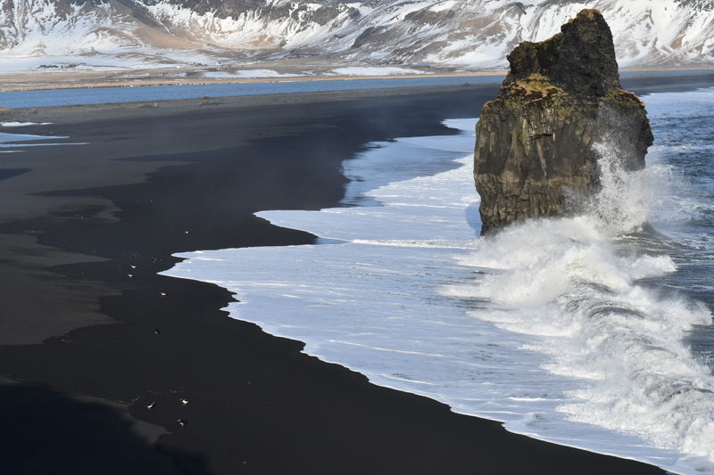 Black Sand Beach: Witness the dramatic contrast of black sands and white waves at Reynisfjara Black Sand Beach. Haunting beauty and towering basalt columns make it a must-visit on your week-long road trip through Iceland in winter.
